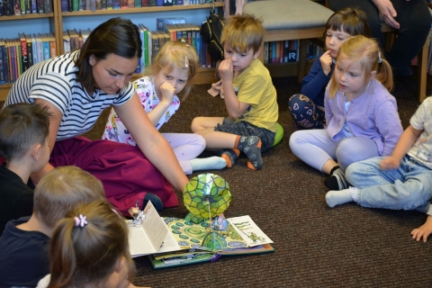 Zdjęcie prezentuje cykl wydarzeń w ramach XXI Tygodnia Bibliotek zorganizowanego przez Bibliotekę Publiczną w Kazimierzu Dolnym: Po niemiecku, hiszpańsku, francusku, włosku, ukraińsku, angielsku … czyta mama i tata”.
