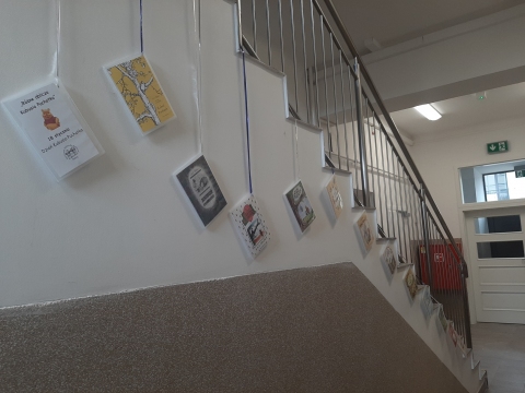 Zdjęcie prezentuje wystawę powieszoną na korytarzu przed biblioteką prezentującą różne okładki książek pt. „Kubuś Puchatek” 