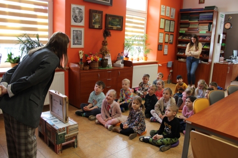 Zdjęcie prezentuje lekcję biblioteczną w Powiatowej Bibliotece Publicznej w Puławach, która odbyła się 16 kwietnia 2026 r. dla grupy Króliczki z Publicznego Przedszkola Integracyjnego w Puławach. Na zdjęciu widać dyrektora biblioteki Katarzynę Adamowską-Kane i przedszkolaki. 
