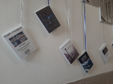 Zdjęcie prezentuje wystawę powieszoną na korytarzu przed biblioteką prezentującą różne okładki książek, w których to właśnie książka jest głównym bohaterem. 