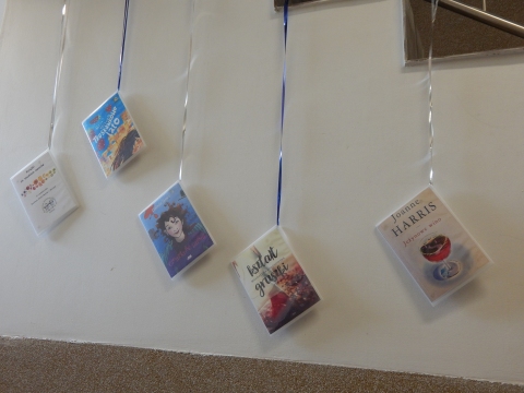 Zdjęcie prezentuje wystawę powieszoną na korytarzu przed biblioteką prezentującą różne okładki książek ze smakiem owoców  tytule.