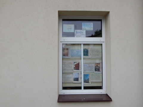 Zdjęcie prezentuje wystawę na oknach Powiatowej Biblioteki Publicznej w Puławach pokazującą książki, których akcja dzieje się nad morzem, w górach i na Mazurach.