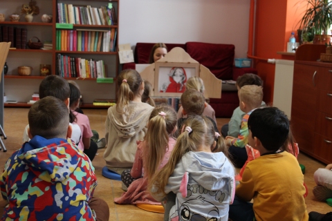 Zdjęcie prezentuje lekcję biblioteczną w Powiatowej Bibliotece Publicznej w Puławach, która odbyła się 16 kwietnia 2026 r. dla grupy Króliczki z Publicznego Przedszkola Integracyjnego w Puławach. Na zdjęciu widać dyrektora biblioteki Katarzynę Adamowską-Kane i przedszkolaki. 