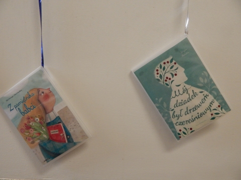 Zdjęcie prezentuje wystawę powieszoną na korytarzu przed biblioteką prezentującą różne okładki książek w których głównymi bohaterami są babcia i dziadek.