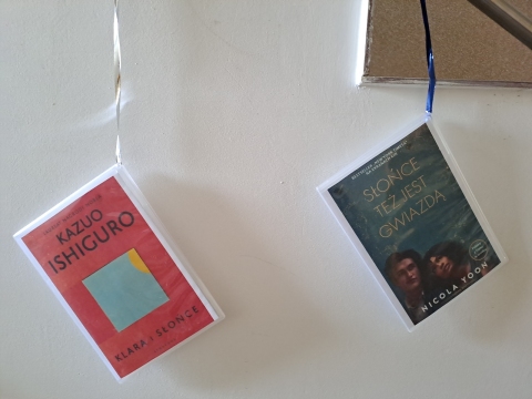 Zdjęcie prezentuje wystawę powieszoną na korytarzu przed biblioteką prezentującą różne okładki książek z wyrazem słońce w tytule.