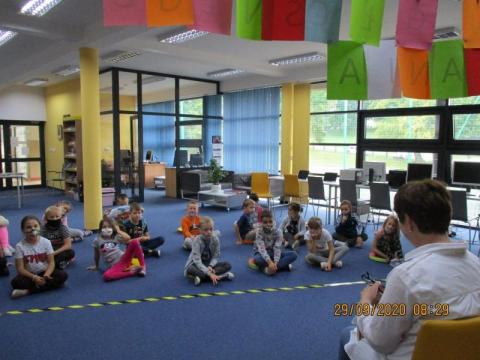 Zdjęcie prezentujące dzieci, uczestników Ogólnopolskiego Dnia Głośnego Czytania w bibliotece gminy Puławy. Pani bibliotekarka czyta przedszkolakom opowiadanie. 