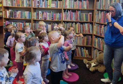 Zdjęcie prezentuje cykl wydarzeń w ramach XXI Tygodnia Bibliotek zorganizowanego przez Bibliotekę Publiczną w Kazimierzu Dolnym: Po niemiecku, hiszpańsku, francusku, włosku, ukraińsku, angielsku … czyta mama i tata”.