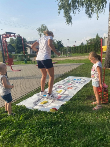 Zdjęcie przedstawia dzieci grające w klasy. 