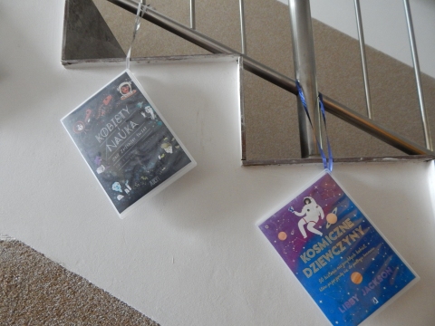 Zdjęcie prezentuje wystawę powieszoną na korytarzu przed biblioteką prezentującą różne okładki książek o inteligentnych, odważnych i silnych kobietach.