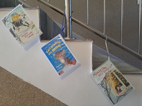 Zdjęcie prezentuje wystawę na oknach Powiatowej Biblioteki Publicznej, która promuje książki, których akcja rozgrywa się w zimowej scenerii.