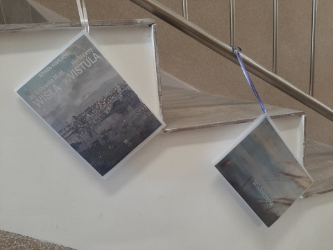 Zdjęcie prezentuje wystawę powieszoną na korytarzu przed biblioteką prezentującą różne okładki książek poświęconych rzece Wiśle. 
