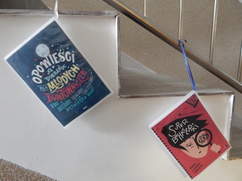 Zdjęcie prezentuje wystawę powieszoną na korytarzu przed biblioteką prezentującą różne okładki książek o inteligentnych, odważnych i silnych kobietach.