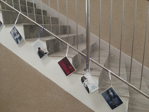 Zdjęcie prezentuje wystawę powieszoną na korytarzu przed biblioteką prezentującą różne okładki książek, których głównym tematem jest miłość. 