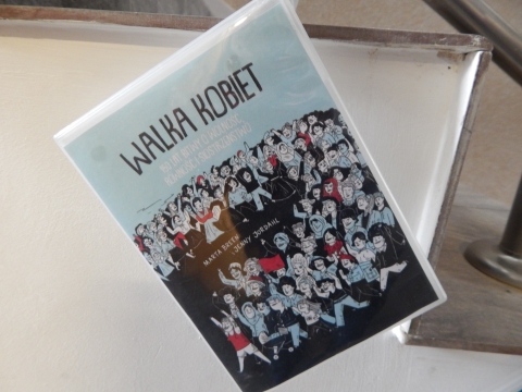 Zdjęcie prezentuje wystawę powieszoną na korytarzu przed biblioteką prezentującą różne okładki książek o inteligentnych, odważnych i silnych kobietach.