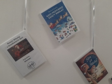 Zdjęcie prezentuje wystawę powieszoną na korytarzu przed biblioteką prezentującą różne okładki książek ze Świętym Mikołajem tytule.