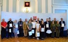 Zdjęcie prezentuje osoby, które otrzymały podziękowania za wsparcie organizacji Rodzinnego Rajdu Rowerowego Puławy–Borowa–Puławy. Na zdjęciu widać 10 mężczyzn i 8 kobiet ustawionych w dwóch rzędach. W tle ścianka z logo i herbem Powiatu Puławskiego. 