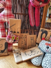 Zdjęcie zapraszające do czytelniczej zabawy, na fotografii książki opakowane w brązowy papier z ilustracjami kotów. 